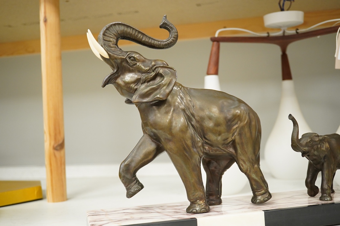 An Art Deco study, three spelter elephants, raised on marble and onyx base, 54cm wide